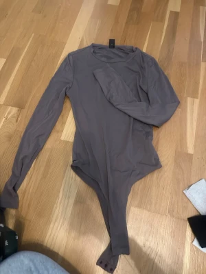 Brun långärmad body - Säljer en enkel och stilren brun body med långa ärmar och rund halsringning. 