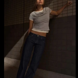 Mörkblå lågmidjade vida jeans från Zara - Snygga mörkblå jeans från Zara med rak passform och klassisk femficksdesign. Jeansen har hög midja och subtila kontrastsömmar. Perfekta för en trendig och avslappnad look. Nytt skick. Lite större i storlek än man tror 