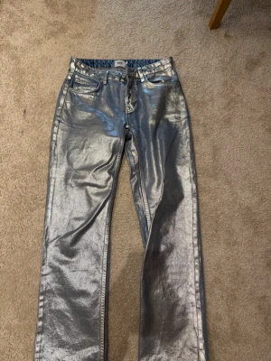 Silvriga raka jeans från lager 157 - Säljer ett par riktigt coola silvriga jeans från lager 157 med rak passform. Jeansen har klassisk femficksdesign och metallisk finish som verkligen sticker ut. Perfekta för dig som vill ha något unikt och trendigt i garderoben. 