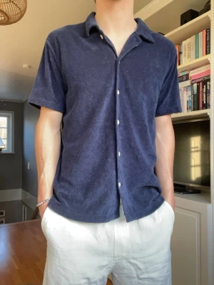 East West frotté skjorta – marinblå – strl M - Snygg kortärmad frotté-skjorta från East West i mörkblå färg. Perfekt till sommaren med shorts eller linnebyxor.  • Märke: East West • Storlek: M • Material: frotté • Skick: bra