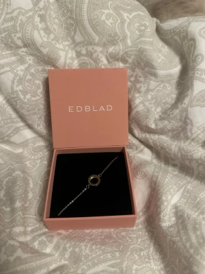 Guldigt armband från Edblad - Snyggt armband från Edblad med tunn guldfärgad kedja och en rund cirkel i mitten dekorerad med små glittrande pärlor. Kommer i original ask. Perfekt accessoar för dig som gillar stilrena smycken med en touch av elegans.