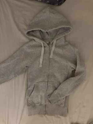 Ljusgrå hoodie från Russemerch - Ljusgrå hoodie med dragkedja från Russemerch. Mjuk bomullsblandning, huva med vita snören och två stora fickor framtill. Säljs då den inte kommer till användning. Använd fåtal gånger.  💕.                         Nypris: 749kr