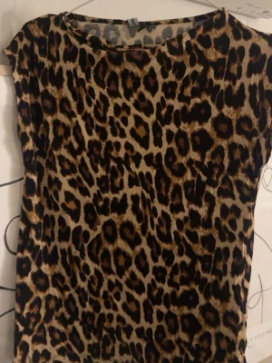 Leopardmönstrad topp med rund hals - Säljer en cool leopardmönstrad topp med rund hals och korta ärmar. Toppens färger går i beige och brunt med svarta detaljer. Perfekt för dig som vill sticka ut och addera lite edge till din outfit.❤️❤️