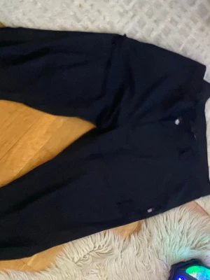 Svarta cargobyxor från Revolution - Säljer ett par svarta cargobyxor från Revolution med raka ben och flera praktiska fickor med dragkedja. Byxorna har bälteshällor och en liten logga på ena benet. Perfekta för dig som gillar streetwear och funktionella detaljer.