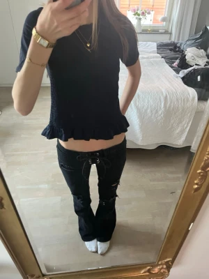 Blå topp - Säljer en snygg blå topp, som är ribbad runt midjan med volanger längst ner i slutet på tröjan,perfekt till dig som vill ha något mer uppklätt.