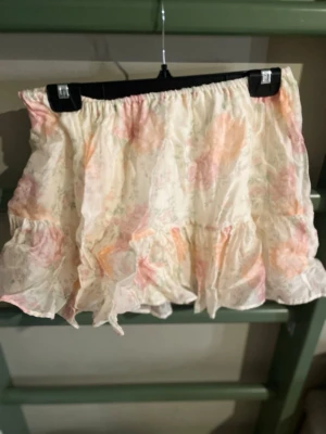 Blommig volangkjol från H&M - Supersöt kort kjol från H&M med blommigt mönster i ljusa pastellfärger. Kjolen har volangdetaljer och resår i midjan för en bekväm passform. Perfekt för dig som gillar en romantisk och lekfull stil.