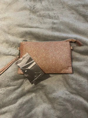 Glittrig kuvertväska från Lycke Oslo - Perfekt accessoar för att lyfta din outfit. Oanvänd och prislappen är kvar. Pris går alltid att diskuter