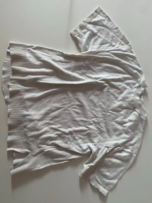 Vit T-shirt   - En vit T-shirt i tjock material som liknar stickat. 