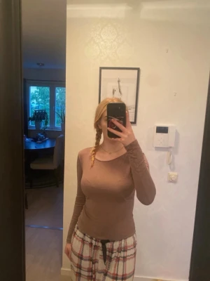 Brun långärmad topp med rund hals - En enkel och stilren brun långärmad topp med rund halsringning. Tunn och lätt, perfekt att matcha med jeans eller kjol. Snygg passform som framhäver siluetten och passar dig som gillar basic plagg med neutral färg.