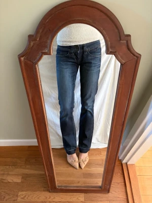 Mörkblå bootcut jeans från Pepe Jeans - Säljer ett par mörkblå lågmidjade jeans med klassisk femficksdesign och snygga broderade detaljer på bakfickorna. Jeansen är tillverkade i 98% bomull. Storlek: W29/L32