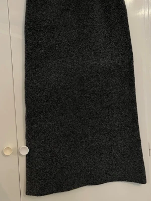 Mörkgrå långkjol stickad  - Säljer en enkel och stilren mörkgrå långkjol. Kjolen har rak passform och är perfekt för dig som gillar minimalistisk stil. Inga synliga detaljer eller mönster, bara klassisk och tidlös design.