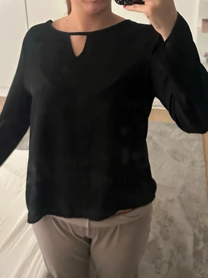 Svart blus med cut out-detalj - Stilren svart blus med lång ärm och en snygg cut out-detalj vid halsringningen. Blusen har en rak passform och är perfekt att matcha med både jeans och kostymbyxor. Blusen är från Shein💓