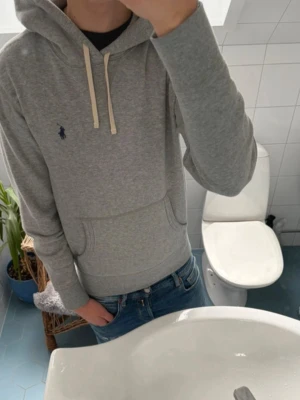 Grå Ralph Lauren Hoodie - Tja! Säljer en sjukt snygg och populär Ralph Lauren Hoodie. Otroligt skönt material och väldigt bra passform. 10/10 Skick inga defekter inget. Nypris ~2300kr. Hör av dig om du har något fundering!