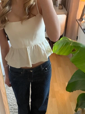 Vit volangtop med knyt i ryggen - Säljer en söt vit linnetopp med volang och svart roset på ryggen. 💕