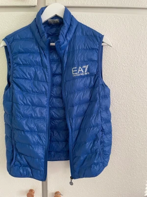Blå Ea7 Väst - Skick 8/10 Ingår en liten påse till västen. Den är väldigt liten, tycker inte att den är en M, passar mer som XS eller möjligen S. 