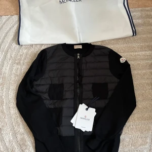 Svart cardiganjacka från Moncler - Snygg svart cardiganjacka från Moncler i storlek M. Lite mindre i storlek, passar en S.   Perfekt vårjacka.  Den är fortfarande i nyskick eftersom jag inte använt den 