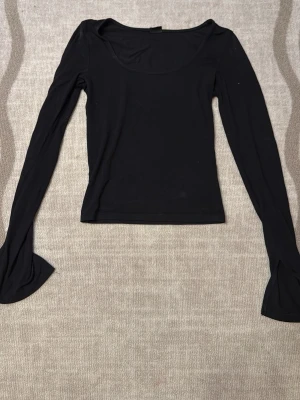 Svart långärmad topp Gina Tricot - Säljer en svart långärmad topp från Gina Tricot i stretchigt material. Toppen har en rundad urringning och sitter tight mot kroppen, perfekt att styla till olika outfits. Enkel och stilren design som passar till det mesta.