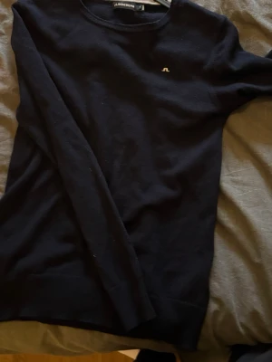 Mörkblå stickad tröja J.Lindeberg - Snygg mörkblå stickad tröja från J.Lindeberg med rund halsringning och diskret logga broderad på bröstet. Tröjan har långa ärmar och är tillverkad i ett mjukt, tunt material som passar perfekt till lager på lager. Den är storlek m men passar s/xs. Pris kan diskuteras vid snabb affär.
