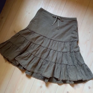 Grön volangkjol med knytband - Grön kjol från Esprit med flera volanger och ett knytband i midjan. Kjolen har en avslappnad passform nedtill. Perfekt för dig som gillar boho-stil och vill ha något bekvämt och snyggt!