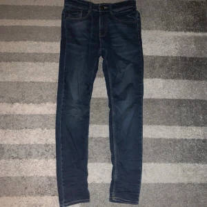 Mörkblå slim fit jeans - Snygga mörkblå slim fit jeans med klassisk femficksdesign och kontrastsömmar. Jeansen har en smal passform och är tillverkade i ett stretchigt denimtyg som ger bra komfort. Perfekta för en trendig och avslappnad stil.