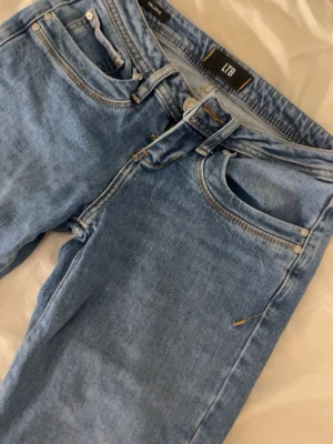 Blå jeans från LTB - Snygga blå jeans från LTB med klassisk femficksdesign och raka ben. Jeansen har ljusblå tvätt och kontrastsömmar. Jeansen är i storlek W24 L30. Dom är knappt använda så skulle säga dom är som nya, inga defekter på dom alls. Säljer på grund av att dom e för små för mig och kan därför inte visa dom på