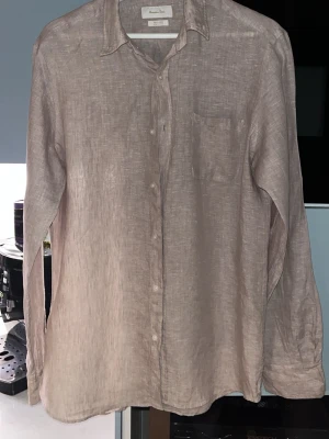 Beige linneskjorta från Massimo Dutti - Snygg beige skjorta i linne från Massimo Dutti. Klassisk modell med lång ärm, bröstficka och knappar framtill. Perfekt för en avslappnad men ändå stilren look. Luftigt material som passar bra till varmare HS-dagar.