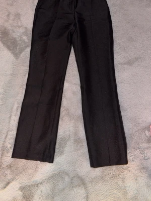 Svarta raka kostymbyxor - Snygga svarta raka kostymbyxor med pressveck. Perfekta till en stilren look och passar till många olika outfits. Använda 2 gånger.