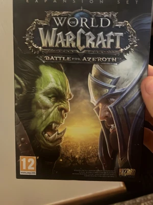 World of Warcraft: Battle for Azeroth - World of Warcraft: Battle for Azeroth är en expansion till det klassiska onlinespelet. Omslaget är svart med fantasyinspirerad konst och logotyp i silver och blått. Fodralet är gjort av kartong och plast. Perfekt för dig som gillar episka äventyr och stora slag mellan Alliance och Horde.