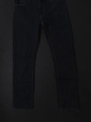 GANT Mörkblå raka jeans  - Snygga mörkblå jeans från Gant med raka ben och klassiska bakfickor. Jeansen har en tidlös design och är tillverkade i denim med kontrastsömmar. Perfekta för dig som gillar en enkel och stilren look.