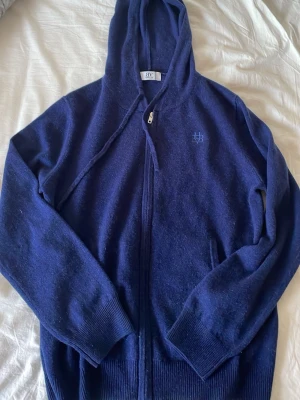 Mörkblå hoodie från Bvaldi - Säljer min mörkblå hoodie från Bvaldi som jag har aldrig använt den har en dragkedja framtill och broderad logga på bröstet. . Klassisk huva och ribbade muddar vid ärmar och nederkant. Perfekt för en avslappnad stil.