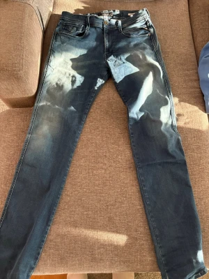 Blå slim fit jeans från Replay - Snygga blå slim fit jeans från Replay, modell Anbass. Jeansen har klassisk femficksdesign, dragkedjegylf och diskreta slitningar för en cool look. Perfekta för dig som gillar en smal passform och stilren design.