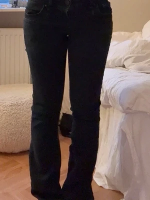 Svarta lowwaist bootcut jeans från LTB - Snygga svarta bootcut jeans från LTB, modell Valerie. Stretchigt material för skön passform. De är väldigt låg midjas och har en mörk mörk blå färg som även kan se svart ut