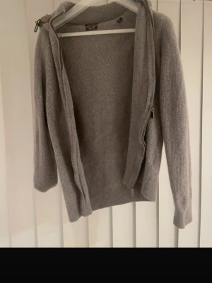 Massimo dutti  - Mysig grå stickad hoodie från Massimo dutti med dragkedja framtill och en vadderad beige huva. Skulle säga att den passar folk under 175 kan skick mer bilder och måtten. Har du frågor och funderingar är de bara att skriva🙂kan diskutera priset vid snabbaffär😊