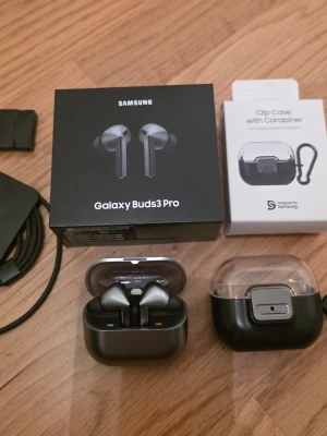 Samsung Buds3 Pro + Samsung hörlursfodral - Säljer ett par Samsung Buds3 Pro med extra original hörlursfodral. De är i perfekt skick, har använt extra fodralet/hörlursfodralet sen dag 1 så tar man ut hörlurarna med laddningsfodralet från hörlursfodralet ser de ut som nya.  Säljer pga. In-ear hörlurar är inget för mig.  Bilden; Original box, Buds 3 hörlurarna i laddningsfodralet, oanvända hörlursploppar, oanvänd extra sladd som man får med, sen original Samsung Clip Case/hörlursfodral. 