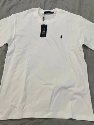 Vit t-shirt från Polo Ralph Lauren - Vit t-shirt från Polo Ralph Lauren med klassisk logga broderad på bröstet, nyskick. Hör av dig vid frågor och funderingar!!