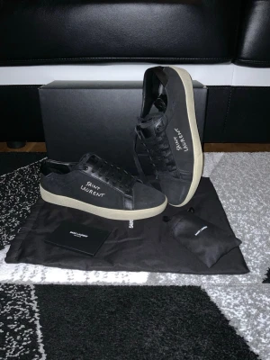 🚨INTRESSEKOLL🚨Saint Laurent Skor - Snygga svarta sneakers från Saint Laurent med vit logga på sidan och beige sula. . Allt OG ingår alltså låda, 2 dustbag, 1 saint laurent kort, 1 påse med 2 nya snören och självklart skorna. Skorna är givetvis äkta. Vill bara uppmärksamma att det ända defekten är att den har tappat lite färg på insidan i högra skon men absolut inget som syns när man har på sig dem. (Bild nummer 5). In princip ganska nya. Skriv om du är intresserad så kan vi snacka om priset💯❤️