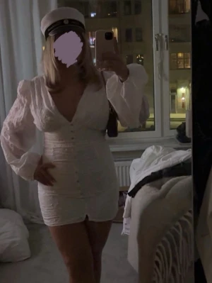 Vit kort klänning med puffärm - Kort vit klänning med v-ringning och långa puffärmar. Klänningen har knappar framtill och markerad midja. Perfekt till student eller sommarens firanden. Snygg och feminin passform. Aldrig använd❤️❤️