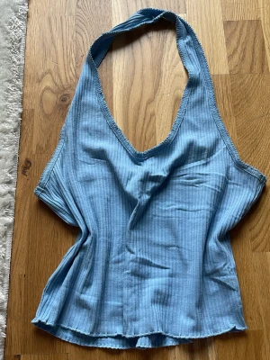 Ljusblå ribbad halterneck topp - Ljusblå ribbad linnetopp med halterneck och v-ringning. Materialet känns mjukt och stretchigt.