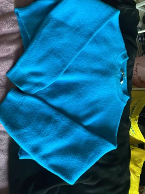 Turkosblå stickad tröja - En enkel och snygg turkosblå stickad tröja med rund hals och långa ärmar. Tröjan har en mjuk och lite fluffig struktur som gör den extra mysig. Perfekt att dra på sig när det är kyligt ute.bilder stämmer inte riktigt med färg nyansen på tröjan .