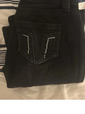 Svarta jeans med nitar från Gina Tricot - Snygga svarta jeans från Gina Tricot med dekorativa nitar på bakfickan. Jeansen har klassisk femficksmodell, bälteshällor och är tillverkade i ett stretchigt denimtyg. Perfekta för dig som vill ha en cool detalj på dina jeans.