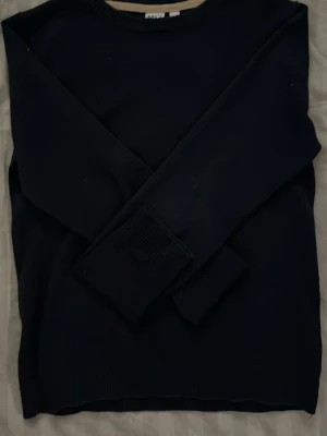 Svart basic tröja med rund hals - En stilren svart tröja med rund halsringning och långa ärmar. Perfekt för lager-på-lager och enkel att matcha med olika outfits. Tröjan har ribbade muddar vid ärmslut och hals.