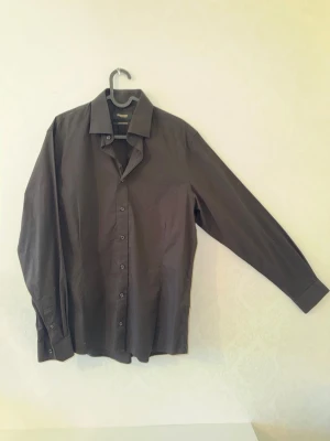 Svart skjorta från Dressmann - Snygg svart skjorta från Dressmann Premium Collection i storlek L. Skjortan är tillverkad i stretchig bomull och har klassisk krage.  Perfekt för dig som vill ha en stilren och enkel look.