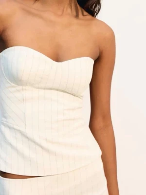 Vit randig axelbandslös korsettopp - Trendig vit korsettopp med tunna vertikala ränder och axelbandslös design. Aldrig använd. Lapp kvar