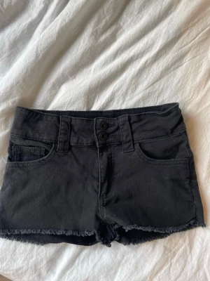 Svarta jeansshorts - Svarta jeansshorts med dubbla knappar framtill. Har inte fått någon användning och säljer därför