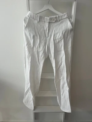 Vita linnebyxor/kostymbyxor från BikBok - Snygga vita linnebyxor/kostymbyxor från BikBok med raka ben. Byxorna har knapp och dragkedja framtill samt sidofickor. Perfekta för en avslappnad och stilren look. Tillverkade i ett luftigt material. Lagt upp ca. 2 cm, ingen märkbar skillnad. Köparen står för eventuell frakt. 