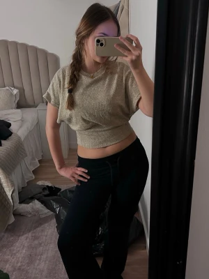 Beige croppad topp med kort ärm - Säljer en beige croppad topp med korta ärmar och rund hals. Toppen har en ribbad, elastisk midja som ger en snygg passform. Perfekt för dig som gillar en enkel men trendig stil.