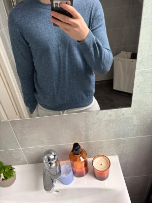 Blå stickad tröja i enkel design från Oscar Jacobson - Säljer en stilren blå stickad tröja med rund hals och långa ärmar. Tröjan har en mjuk och slät yta, perfekt för lager på lager eller att bära som den är. Passar dig som gillar en klassisk och avslappnad look. Vill ni ha fler bilder bara hör av er.