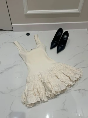 Vit volangklänning från Zara - Zara-klänning i storlek S. Säsongens mest eftertraktade modell - en åtsittande topp med breda axelband och en spektakulär, kraftig rynkad ballongfåll. Väldigt feminin.