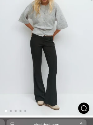 Svarta kostymbyxor från Gina Tricot - Snygga knappt andvända svarta kostymbyxor från Gina Tricot med utsvängda ben och låg midja. Byxorna har klassisk design med fickor bak. Byxorna ger en clean look och är perfekta för en trendig och stilren outfit.