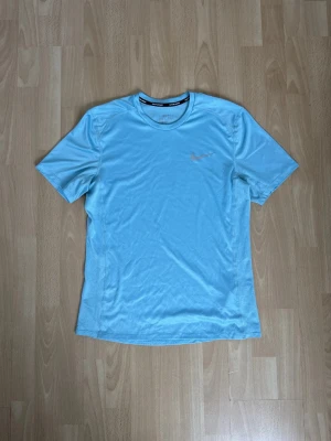 Ljusblå Nike t-shirt - Säljer en ljusblå t-shirt från Nike med klassisk rund hals och korta ärmar. Materialet är lätt och andas, perfekt för sport eller chill. Diskret Nike-logga på bröstet. Enkel och stilren design som funkar till många outfits.